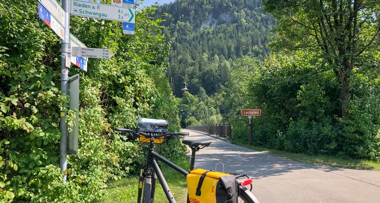 Bicyclette avec un panneau de sentier dans un environnement verdoyant.