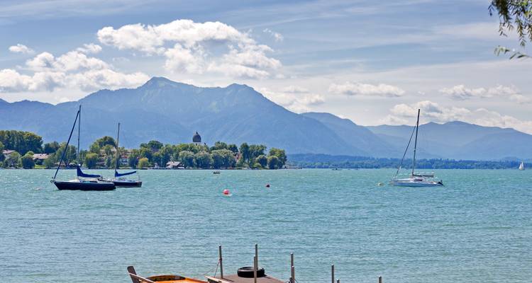 Vue panoramique de voiliers sur un lac avec un arrière-plan montagneux.
