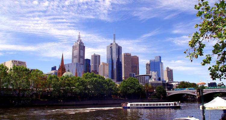 Rivière avec un horizon moderne et des bateaux, sous un ciel nuageux.