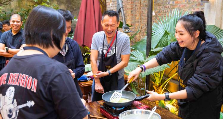 Personas disfrutando de una clase de cocina con un chef al aire libre.