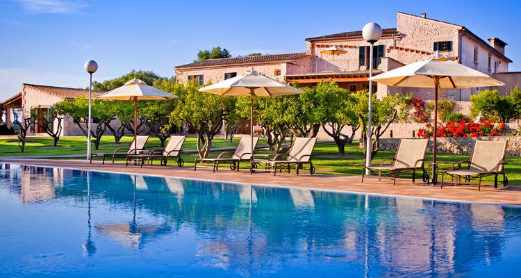 Vue de la piscine avec chaises longues et un bâtiment rustique.