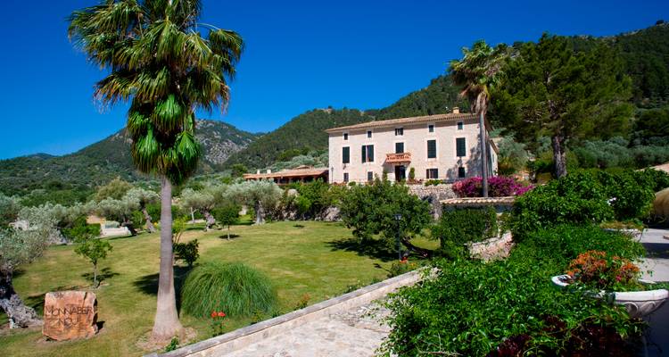 Élégant bâtiment entouré de verdure avec des montagnes en arrière-plan.