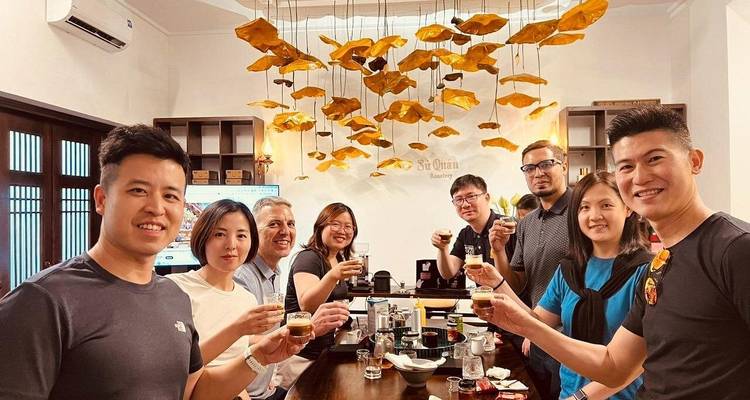 Grupo de visitantes levantando tazas de café para brindar dentro de una elegante cafetería de Hanoi