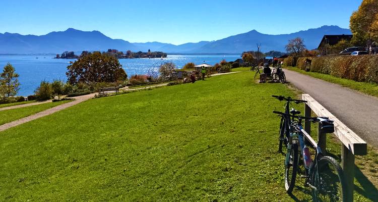 Bicicletas estacionadas cerca de un área con césped con vistas al lago y las montañas.