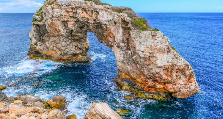 Arche rocheuse naturelle au-dessus des vagues bleues de l'océan.