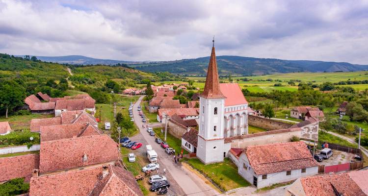 Vue aérienne d'un village rural avec une grande église au toit rouge et un paysage pittoresque.