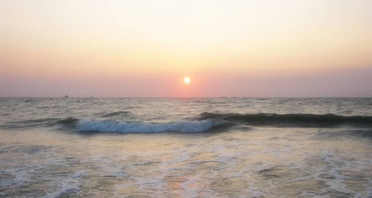 Coucher de soleil sur l'océan avec des vagues qui se brisent.
