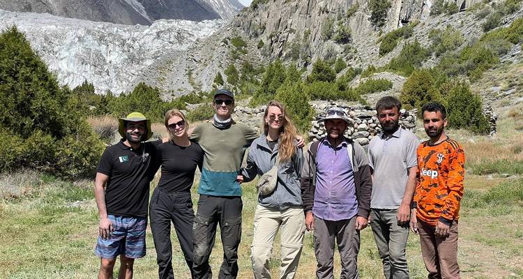 Un groupe de personnes posant devant un glacier et un paysage rocheux.