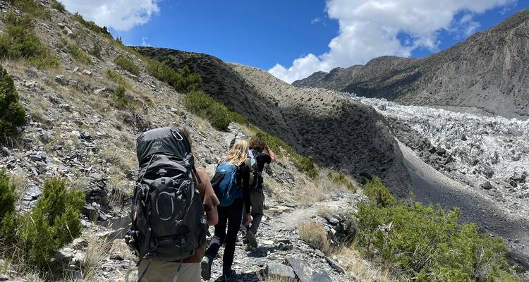Des personnes faisant de la randonnée sur un sentier avec un terrain montagneux.