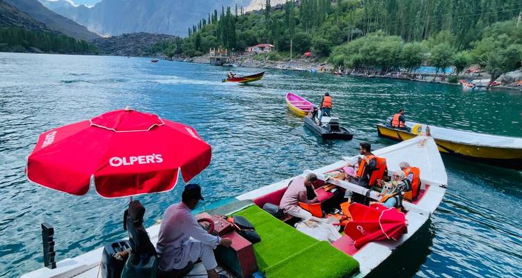 Des gens sur des bateaux colorés dans un lac entouré d'arbres.