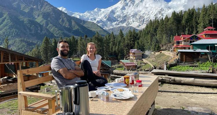 Deux personnes dînant en plein air avec des montagnes en arrière-plan.