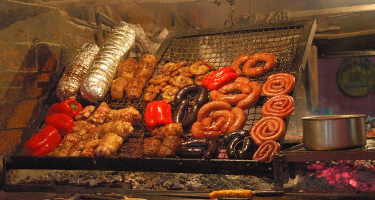 Ein traditionelles argentinisches Asado mit verschiedenen Fleischsorten und Gemüse auf einem Grill.