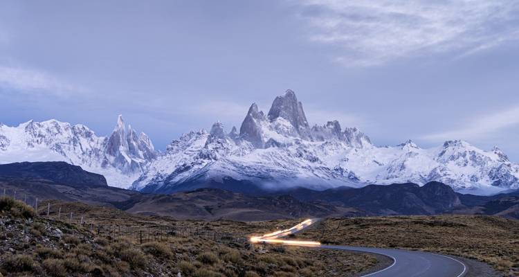 Une route pittoresque menant à des montagnes enneigées au crépuscule.