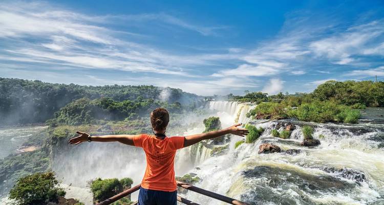 Persona parada con alegría con los brazos extendidos en las Cataratas del Iguazú.
