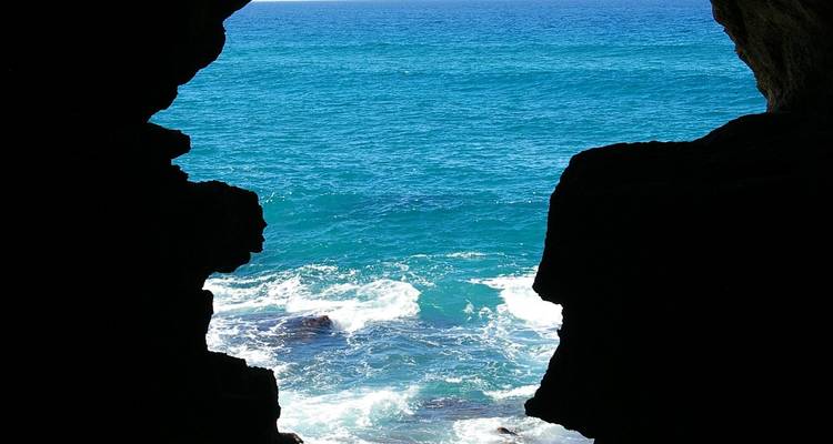Vue de l'océan depuis une formation rocheuse naturelle, les vagues se fracassant contre les rochers.