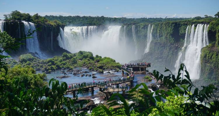 Iguazu-Wasserfälle mit einem Gehweg und Touristen, die die Landschaft betrachten.