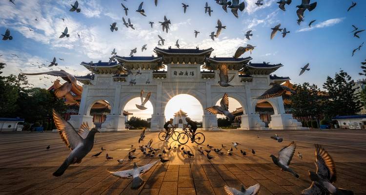 Des cyclistes passant à travers une grande arche avec des pigeons.