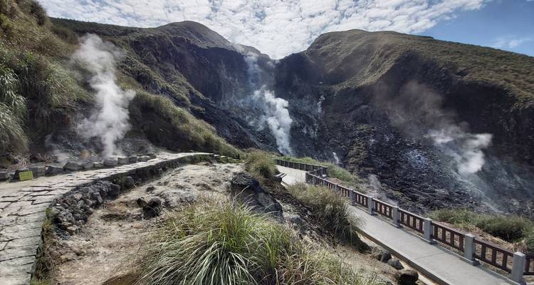 Zone géothermique avec évents fumants et sentiers.