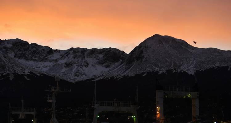 Silhouettes de montagnes au coucher du soleil avec un ciel coloré.