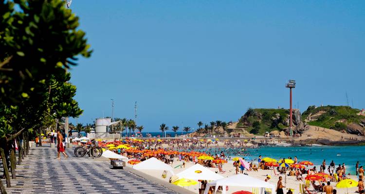 Druk strand met kleurrijke parasols en mensen.