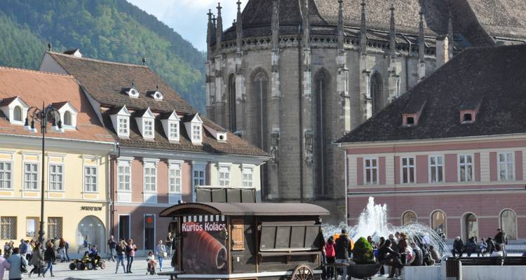 Des gens profitant d'une place historique avec des églises et un chariot de nourriture.