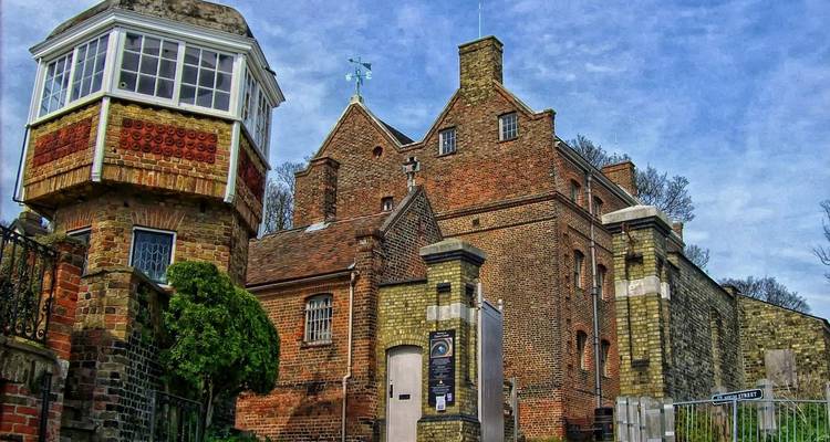 Bâtiment historique en brique avec une tourelle et une girouette.