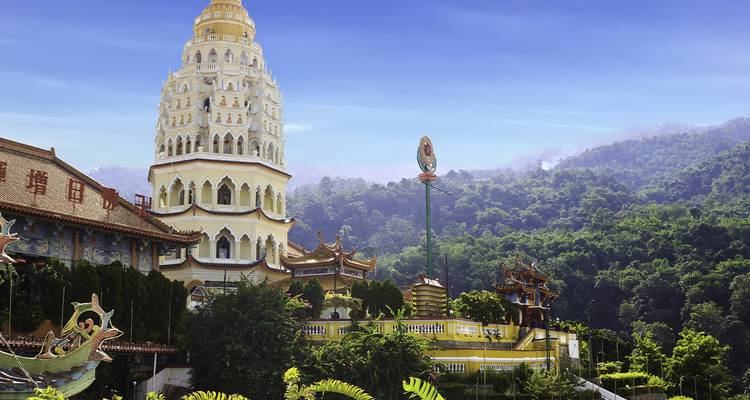 Templo de estilo pagoda con arquitectura intrincada contra un fondo montañoso.