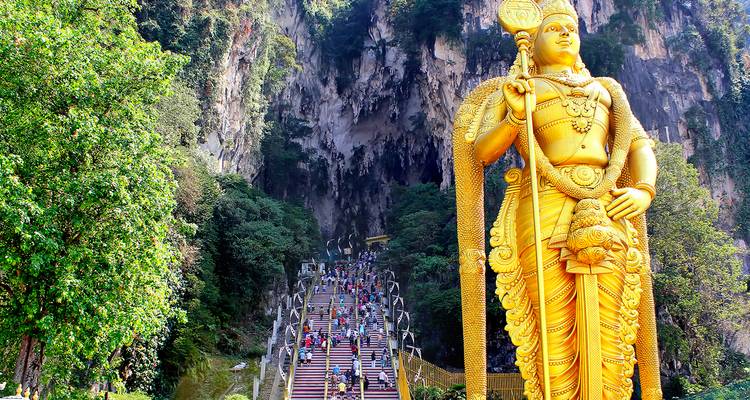 Enorme estatua de Murugan en la entrada de las Cuevas de Batu con un telón de fondo vibrante.