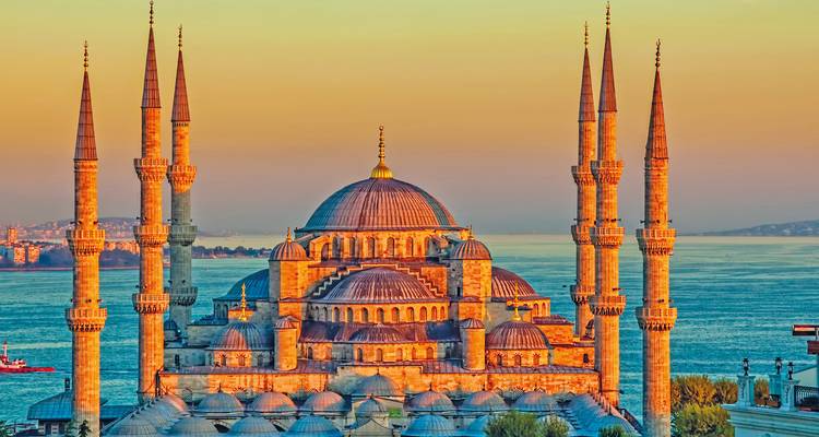 De Blauwe Moskee (Sultan Ahmed Moskee) in Istanbul gloeit in warm zonsondergangslicht met de Bosporus op de achtergrond.