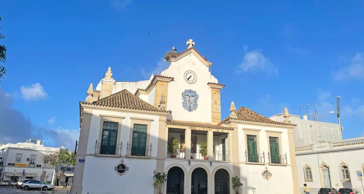 Façade blanche d'un bâtiment historique avec une tour d'horloge.