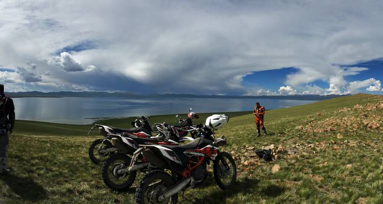 Des motos garées sur une colline herbeuse surplombant un lac.
