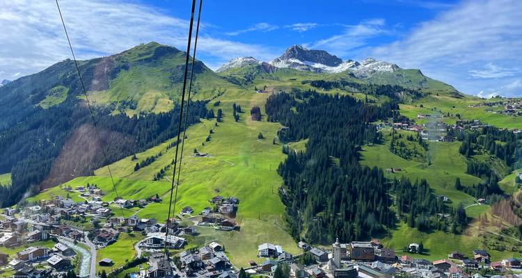 Vue aérienne d'une zone de village montagneux avec des collines vertes.