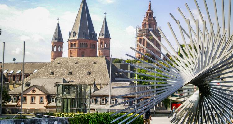 Tours historiques de cathédrale dans un paysage urbain avec sculpture d'art moderne.