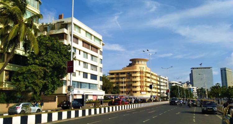 Een drukke stadsstraat met moderne en art deco gebouwen.