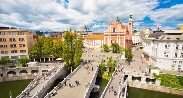 Vue aérienne d'une place urbaine animée avec des ponts et une église historique.