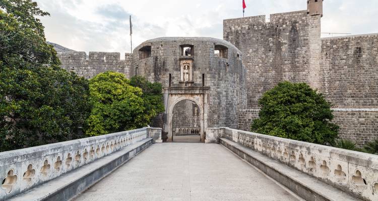 Fortification historique en pierre avec des arbres autour de l'entrée.