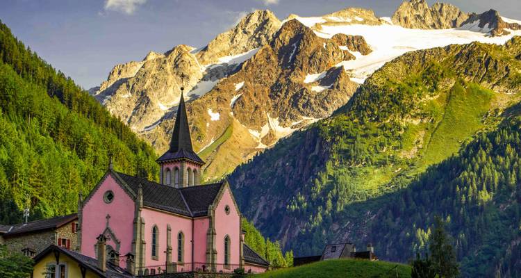 Charmante église rose sur un fond de montagnes enneigées.