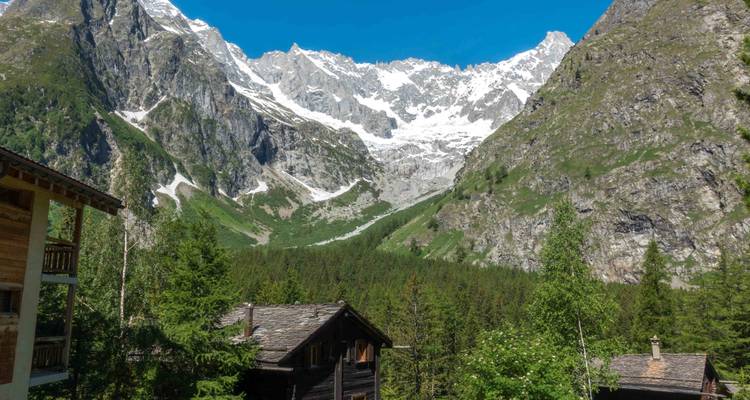 Village de montagne avec des maisons traditionnelles en bois et des sommets enneigés.