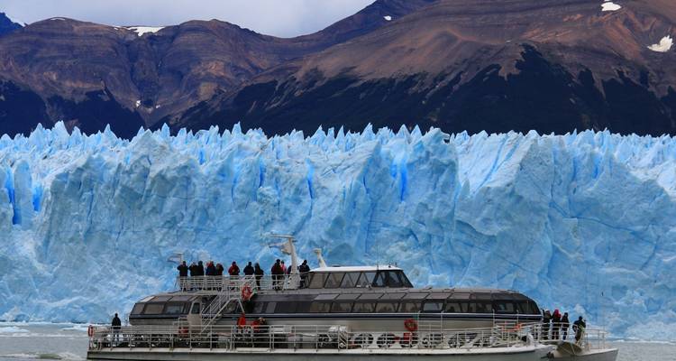 Bateau avec des touristes s'approchant d'un glacier massif.