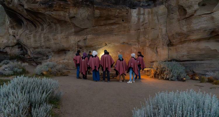Groupe de personnes portant des ponchos traditionnels à l'intérieur d'une grotte.