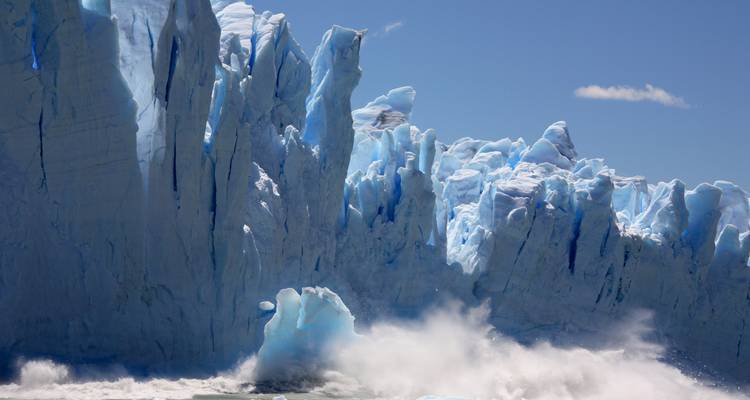 Gros plan d'un glacier avec des pics de glace spectaculaires et des vagues qui se brisent.