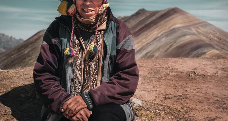 Une personne en vêtements traditionnels, des montagnes en arrière-plan.