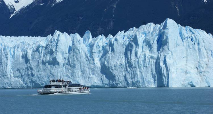 Croisière en bateau près d'un grand glacier avec des montagnes en arrière-plan.