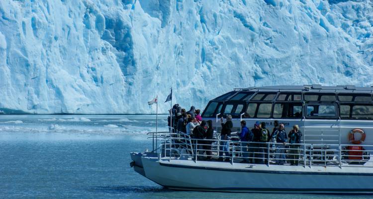 Un bateau avec des touristes observant un glacier.