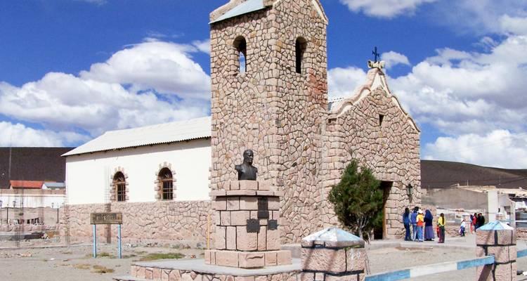 Une église de pierre rustique avec un petit monument au premier plan.