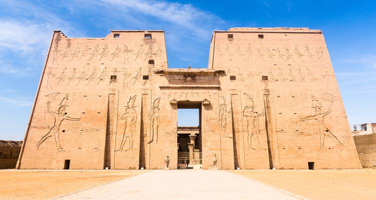 Massive Sandsteinpylone des Edfu-Tempels, geschmückt mit antiken Schnitzereien unter klarem Himmel.