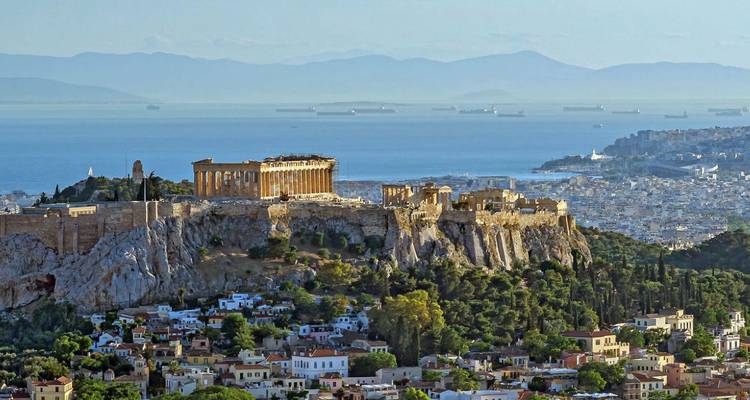 Vista aérea de la Acrópolis de Atenas rodeada de vegetación.