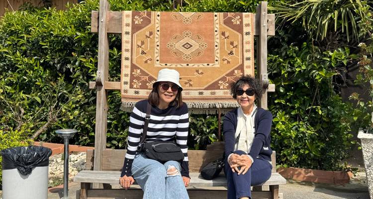 Dos personas sentadas en un banco con un fondo de alfombra.