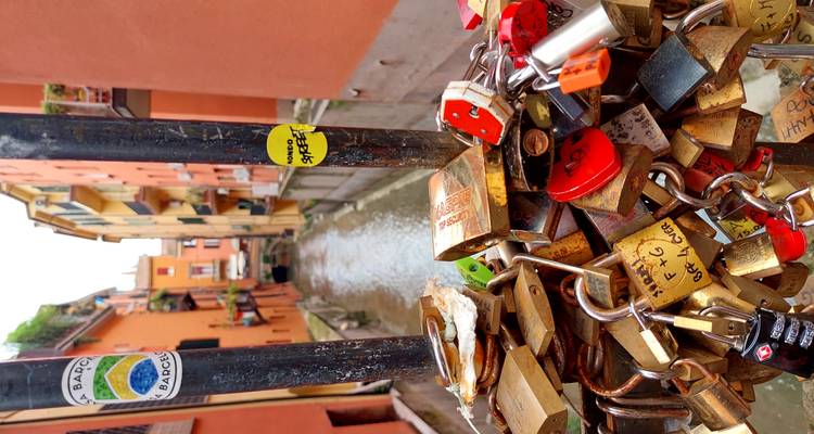 Close view of colorful love locks attached to a railing overlooking Bologna’s small canal