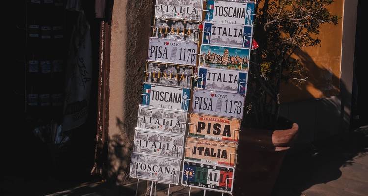 Display rack of souvenir license-plate style signs reading Pisa, Italia and Toscana outside a shop